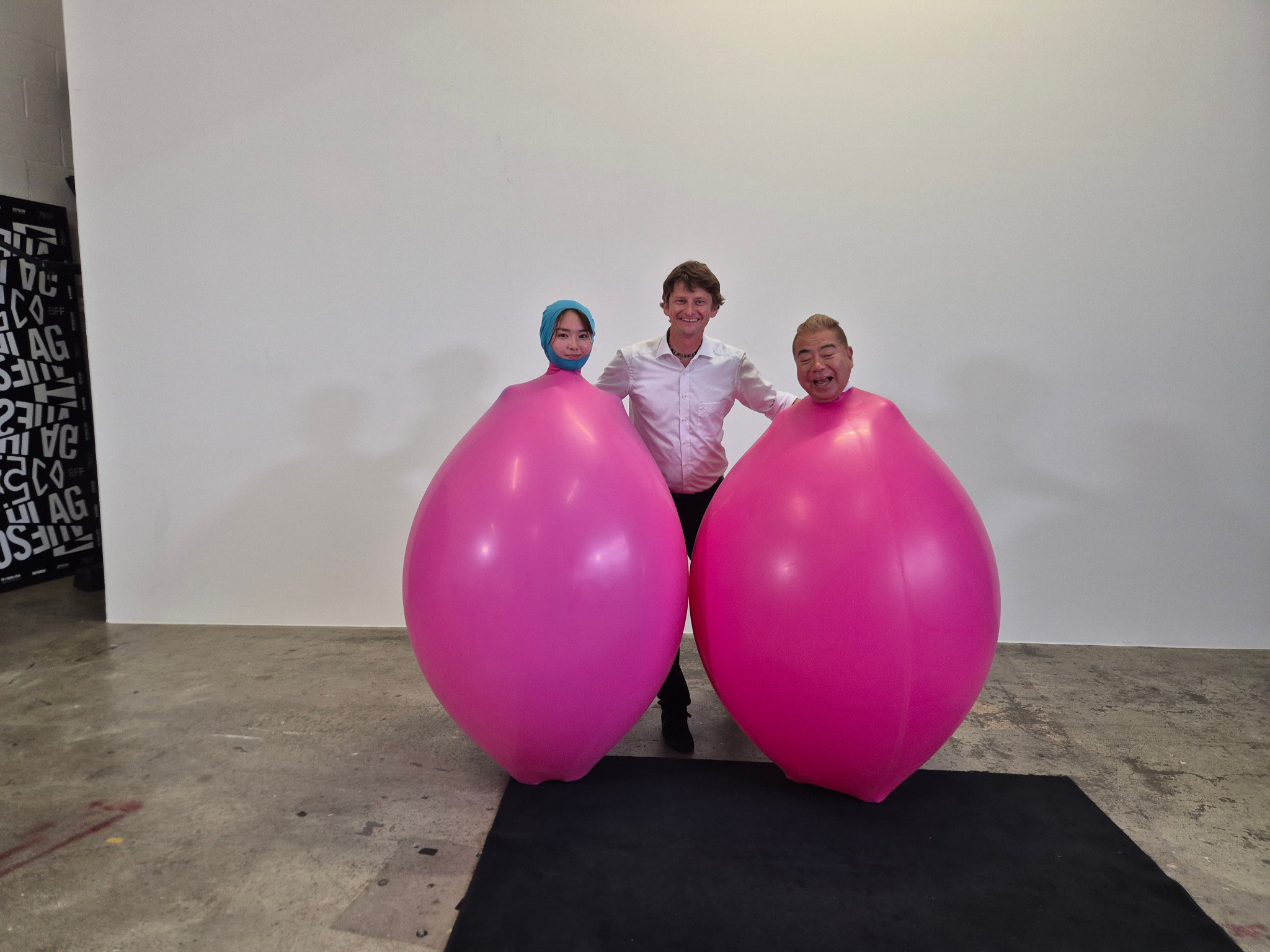 Tobi van Deisner zwischen Yumena Yanai und Tetsurō Degawa in pinken Riesenballons
